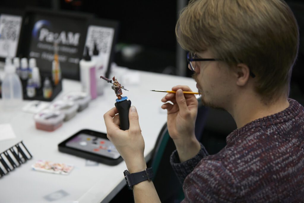 Foto von einem Gast, der eine Brettspiel-Figur bemalt.