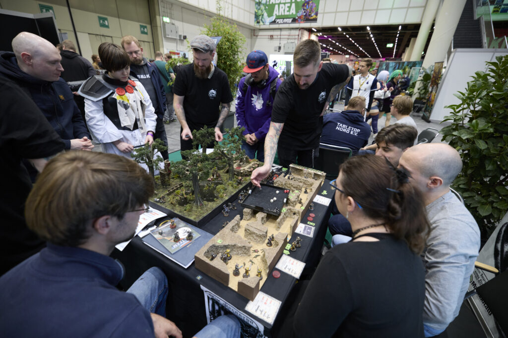 Foto von Gästen, die in der Tabletop Area der POLARIS Convention 2024 ein Brettspiel spielen.