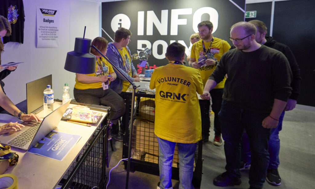 Foto vom offiziellen Informationsstand der POLARIS Convention 2024. Man sieht freiwillige Helfer:innen und Gäste.